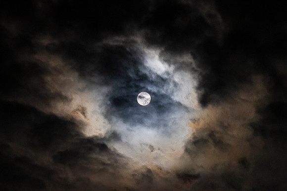Full Moon in the night sky with dramatic clouds