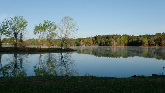 Lake scene with jetty, trees in springtime, still waters
